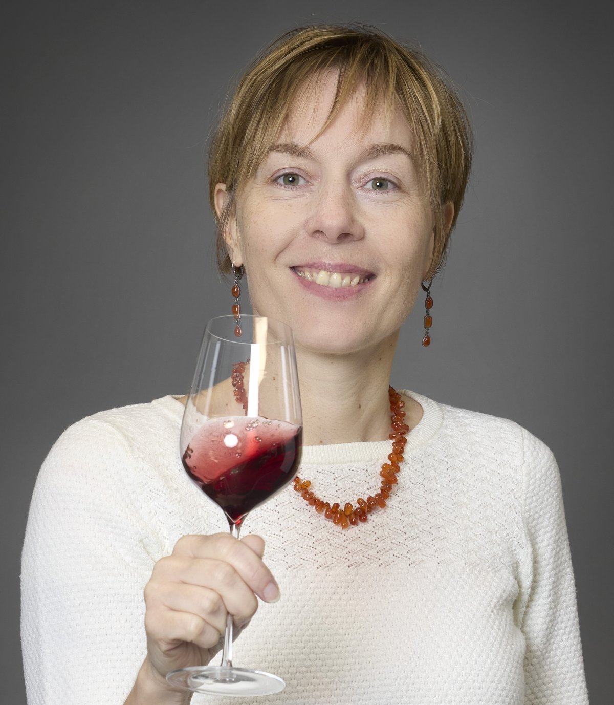 Céline Dandelot, Burgundy wine expert in Beaune, evaluating a glass of red Pinot Noir during a professional wine tasting session.