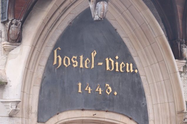 Historical stone inscription of "Hostel-Dieu 1443" at the entrance of the Hospices de Beaune, featured in Céline Dandelot's insider guide.